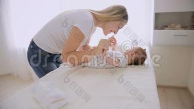 年轻有爱心的母亲和躺在换洗桌子上的小男孩聊天玩耍